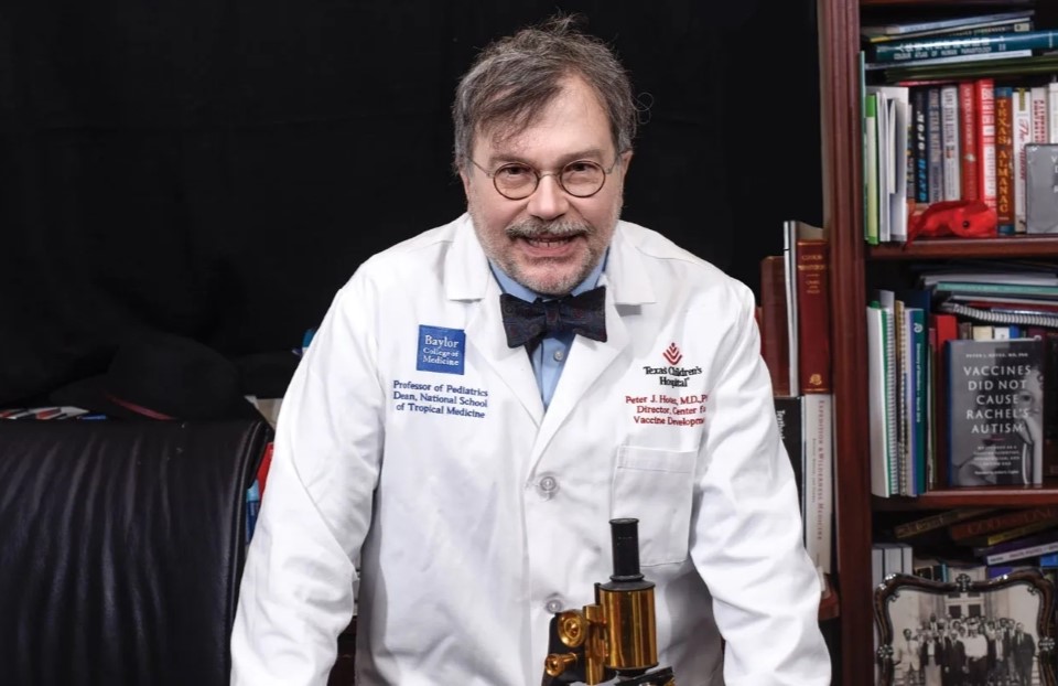 Peter Jay Hotez stands smiling in front of a bookshelf.